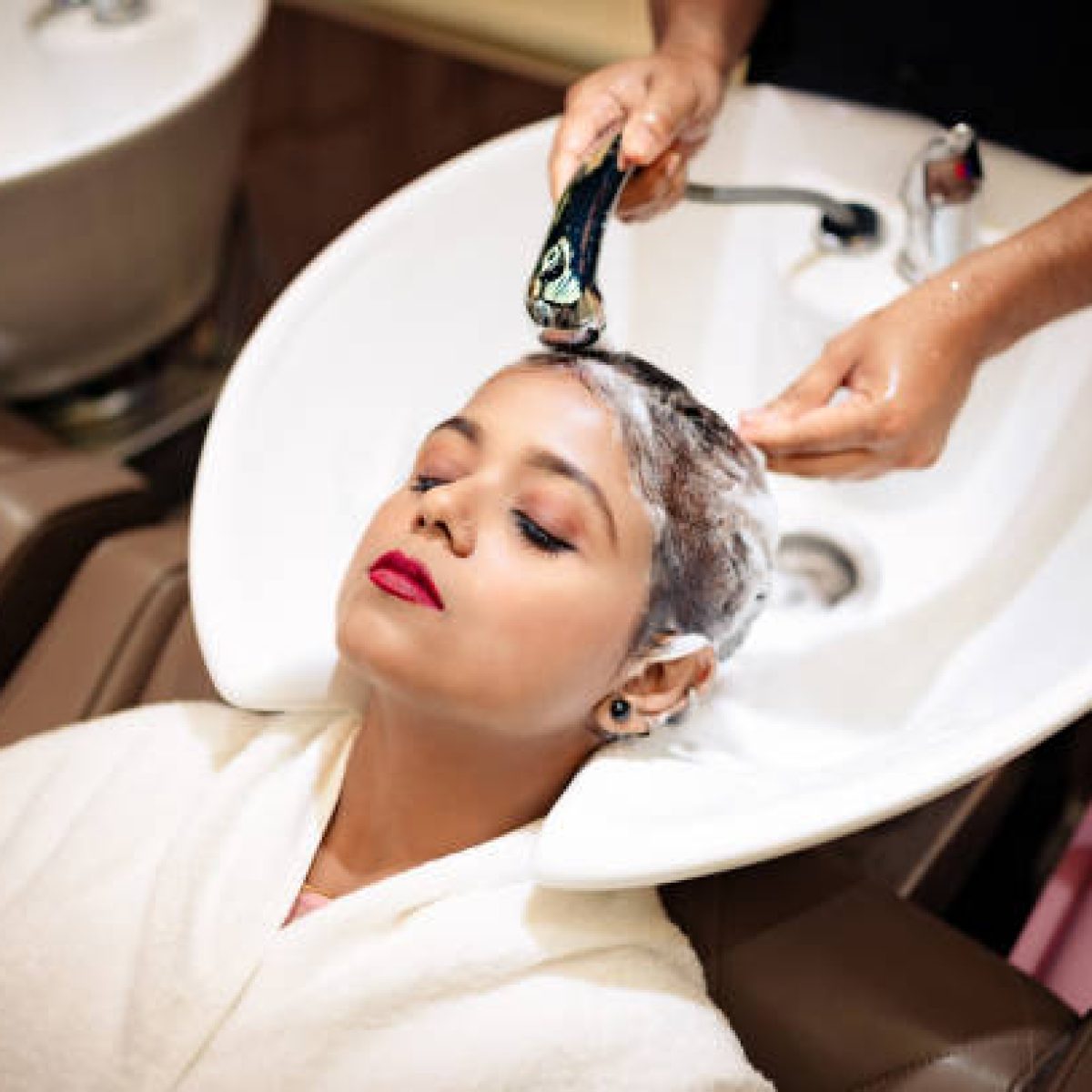 Young woman enjoying while getting her hair washed by professional hairdresser  in a beauty salon.